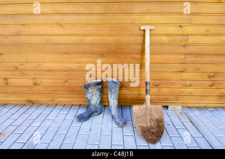 Schaufel und Gummistiefel, basierend auf einer Holzwand Stockfoto