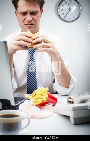 Porträt von angewidert Geschäftsmann Hamburger in der Mittagspause Essen Stockfoto