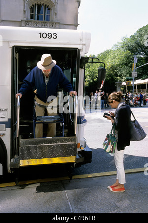 Ältere behinderte Senioren steigen mit einem orthopädischen Gehhilfen aus dem New Yorker Bus. Frau, die Geld für den Transport zählt. Öffentliche Verkehrsmittel USA Stockfoto