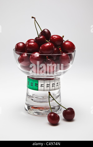 Rote Kirschen in Glasschale mit Maßband Stockfoto