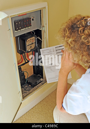 Die steigenden Energiepreise und Rechnungen im Vereinigten Königreich zu betrachten, wie sie ihren Stromzähler liest Frau Stockfoto