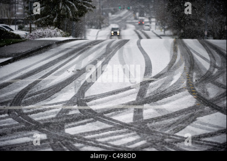 Auto auf der Straße und Reifen verfolgt während Schneesturm in Seattle, Washington, USA Stockfoto