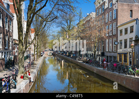 Zwei junge Frauen sitzen Oudezijds Achterburgwal Kanal in der Red Light District (De Wallen) im Frühjahr, Amsterdam, Niederlande Stockfoto