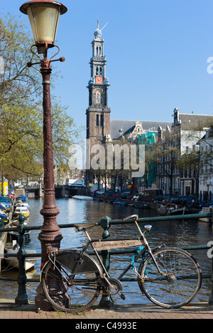 Fahrrad auf Brücke über Prinsengracht mit Turm der Westerkerk (Westertoren) hinter Grachtengordel, Amsterdam, Niederlande Stockfoto