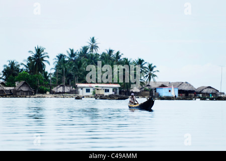 Ansicht eines indigenen Kuna Mannes sein Ruderboot vor einer Insel in San Blas Archipel der Küste von Panama in Mittelamerika Stockfoto