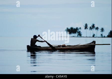 Ansicht eines indigenen Kuna Mannes sein Ruderboot vor einer Insel in San Blas Archipel der Küste von Panama in Mittelamerika Stockfoto