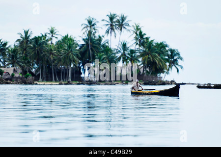 Ansicht eines indigenen Kuna Mannes sein Ruderboot vor einer Insel in San Blas Archipel der Küste von Panama in Mittelamerika Stockfoto