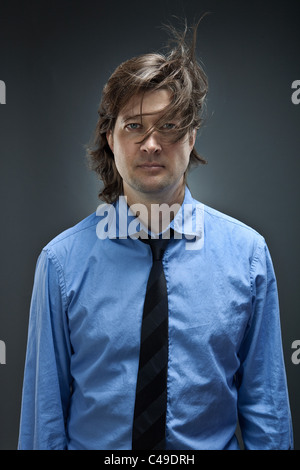 Studio-Porträt der Geschäftsmann in Button-Down-Oxford-Hemd die Kamera frontal gerichtet während seiner braunen Haaren herum bläst. Stockfoto