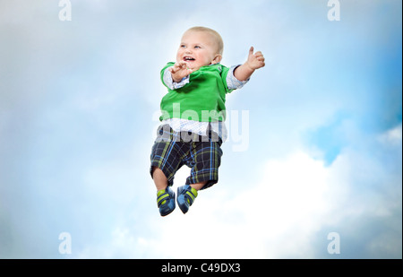 Einen kleinen Jungen in trendige Kleidung fliegen in der Luft vor einem blauen Himmel. Stockfoto