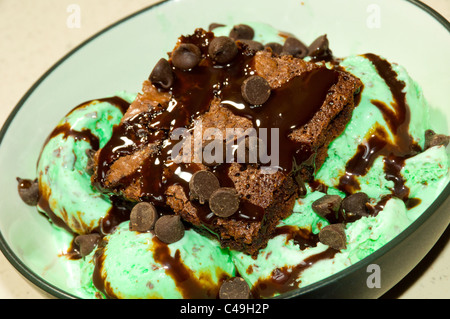 Ein Schokoladen-Brownie mit Schokoladenstückchen und Sirup auf Mint Chocolate Ice Cream gekrönt. Stockfoto