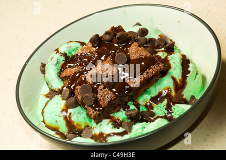 Ein Schokoladen-Brownie mit Schokoladenstückchen und Sirup auf Mint Chocolate Ice Cream gekrönt. Stockfoto