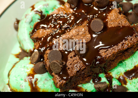 Ein Schokoladen-Brownie mit Schokoladenstückchen und Sirup auf Mint Chocolate Ice Cream gekrönt. Stockfoto