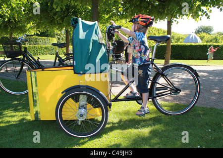 Kleiner Junge mit mit Flamme Helm auf ein Nihola Lastenfahrrad. Stockfoto