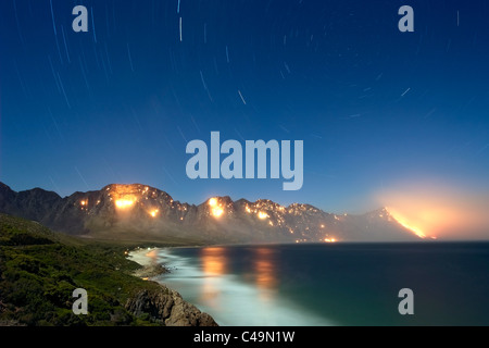 Nacht, Mondschein-Blick auf ein wildes Feuer im Kogel Bay Nature Reserve in der Nähe von Koeël Bay in der False Bay, Western Cape, Südafrika. Stockfoto