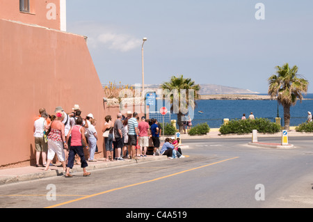 Eine Schlange von Touristen warten an einer Bushaltestelle in Bugibba, Malta auf den nächsten Bus Richtung Kunsthandwerk Dorf am Ta'Qali und Mdina Stockfoto