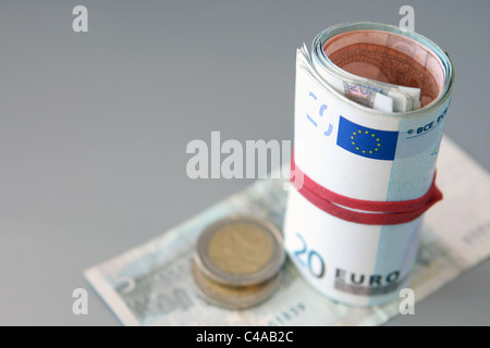 Euro-Münzen und ein Bündel von Euro-Banknoten auf aufgerollt einen 5 Euro-Schein Stockfoto