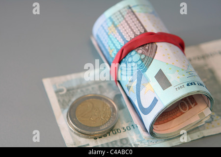 Euro-Münzen und ein Bündel von Euro-Banknoten auf aufgerollt einen 5 Euro-Schein Stockfoto