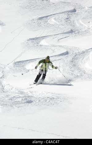 Ein Mann Ski tragen einen Rucksack abseits der Piste in frischem Schnee unter blauem Himmel in Dizin Resort Teil des Elburs-Gebirges Iran Stockfoto