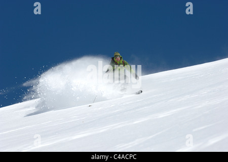 Ein Mann Ski tragen einen Rucksack abseits der Piste in frischem Schnee unter blauem Himmel in Dizin Resort Teil des Elburs-Gebirges Iran Stockfoto