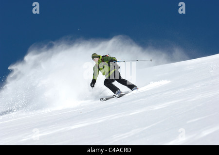 Ein Mann Ski tragen einen Rucksack abseits der Piste in frischem Schnee unter blauem Himmel in Dizin Resort Teil des Elburs-Gebirges Iran Stockfoto