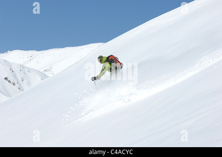 Ein Mann Ski tragen einen Rucksack abseits der Piste in frischem Schnee unter blauem Himmel in Dizin Resort Teil des Elburs-Gebirges Iran Stockfoto