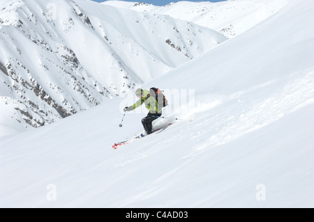 Ein Mann Ski tragen einen Rucksack abseits der Piste in frischem Schnee unter blauem Himmel in Dizin Resort Teil des Elburs-Gebirges Iran Stockfoto