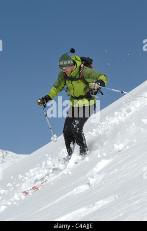 Ein Mann Ski tragen einen Rucksack abseits der Piste in frischem Schnee unter blauem Himmel in Dizin Resort Teil des Elburs-Gebirges Iran Stockfoto