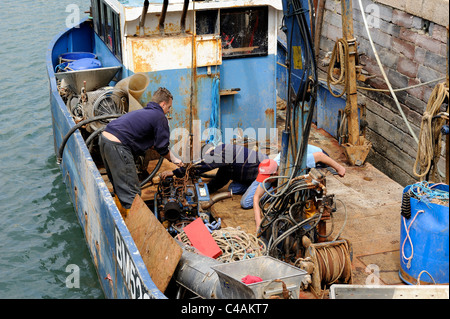 Besatzung eines Fischerbootes Einbau des Motors, unter Deck Brixham Devon England uk Stockfoto