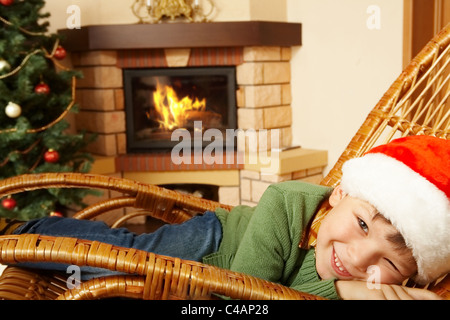 Foto von süsser Boy mit Santa Mütze vorgibt, schlafen im Schaukelstuhl Stockfoto