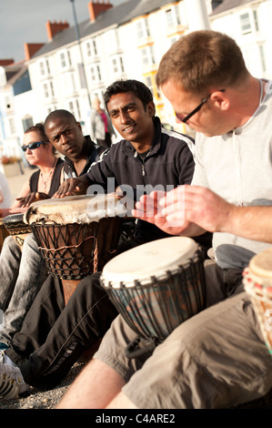 Eine gemischte ethnische Gruppe von Männern, die Teilnahme an eine improvisierte Trommeln Sitzung auf Aberystwyth Promenade, Wales UK Stockfoto