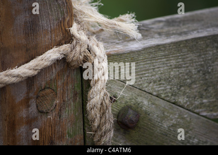 Ein hölzernes Tor mit einem alten Seil gebunden um Vieh zu halten, Stockfoto