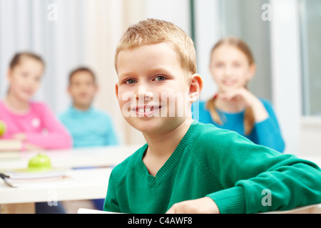 Süße junge Blick in die Kamera auf Grund seiner Klassenkameraden Stockfoto