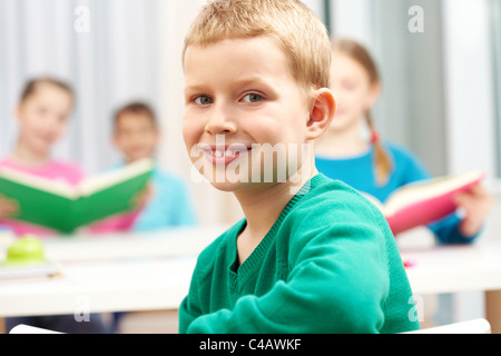 Süße junge Blick in die Kamera auf Grund seiner Klassenkameraden Stockfoto