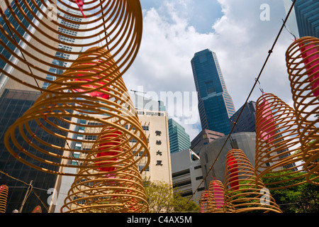 Singapur, Singapur, Raffles Place. Spirale Weihrauch Spulen mit Skyline der Stadt im Hintergrund bei Wak Hai Cheng Bio Tempel. Stockfoto