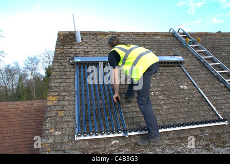 Ingenieure, die Installation solar thermische evakuierten Röhre Array auf dem Dach eines inländischen Hauses Erneuerbare Wärme und Warmwasser Stockfoto