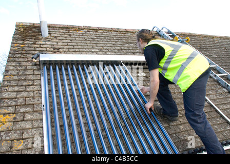 Ingenieure, die Installation solar thermische evakuierten Röhre Array auf dem Dach eines inländischen Hauses Erneuerbare Wärme und Warmwasser Stockfoto