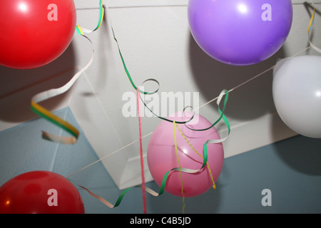 Eine Feier mit vielen bunten Luftballons hängen an der Decke oder auf dem Boden, ideal für eine Kinder-Geburtstags-Party. Stockfoto