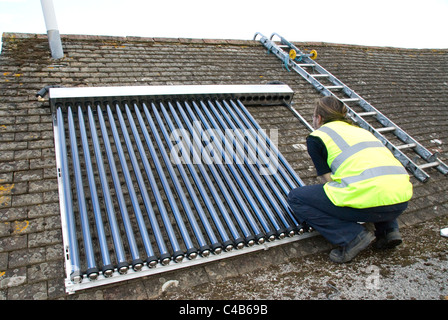 Ingenieure, die Installation solar thermische evakuierten Röhre Array auf dem Dach eines inländischen Hauses Erneuerbare Wärme und Warmwasser Stockfoto