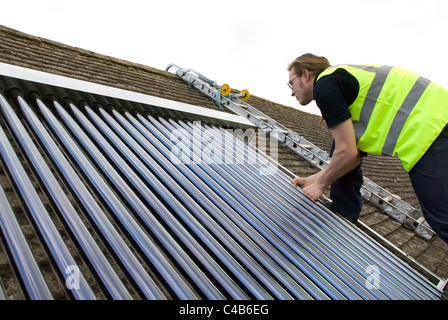 Ingenieure, die Installation solar thermische evakuierten Röhre Array auf dem Dach eines inländischen Hauses Erneuerbare Wärme und Warmwasser Stockfoto