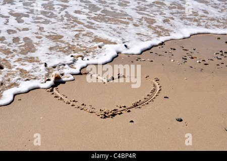 Die Form eines Herzens in den Sand am Meer ausgehöhlt Stockfoto