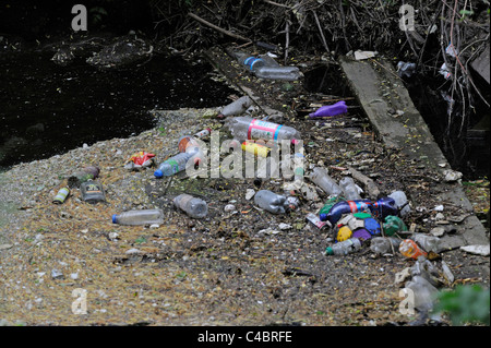 Ausrangierte Plastikflaschen und anderem Müll lag auf einem langsam laufenden Fluss oder Bach. Stockfoto