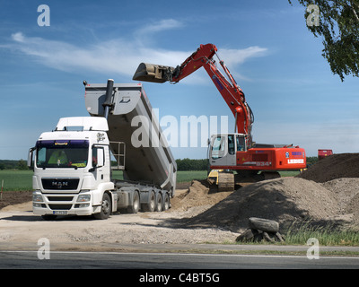 Löffelbagger entladen ein Dump Lastwagen mit Kies auf einer Baustelle in der Nähe von Tespe, Niedersachsen, Deutschland Stockfoto