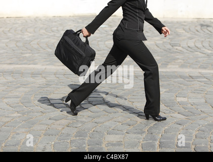 Geschäftsfrau die Beine, wie sie in Eile auf einer gepflasterten Straße Fuß ist. Stockfoto