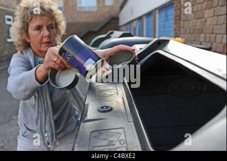 Mittlere gealterte Frau mit einem Feld von Flaschen und Dosen für das recycling im Vereinigten Königreich Stockfoto