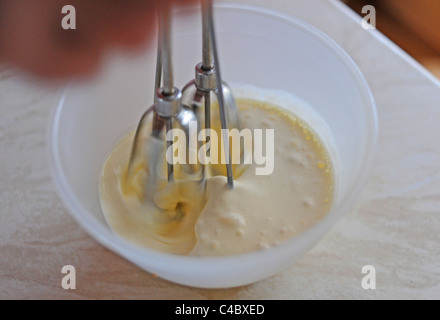 Frau mit einer alten altmodischen Hand Schneebesen in einer Schüssel Sahne in Küche UK Stockfoto