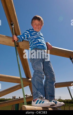 Ein sieben Jahre alter Junge auf einem Klettergerüst im Vereinigten Königreich Stockfoto