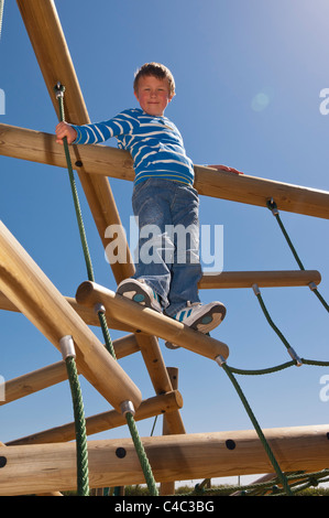 Ein sieben Jahre alter Junge auf einem Klettergerüst im Vereinigten Königreich Stockfoto