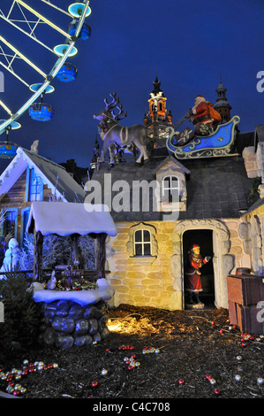 Ein Portraitbild zeigt eine Yule Tide-Szene auf einem Weihnachtsmarkt in Lille Frankreich. Santa in seinem Schlitten auf dem Dach eines Hauses anzeigen Stockfoto