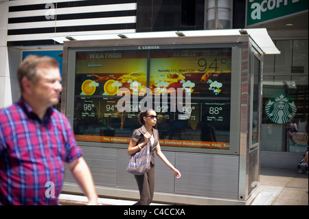 Besucher pass ein Leuchtschild mit den Wetterbericht auf dem Times Square in New York Stockfoto