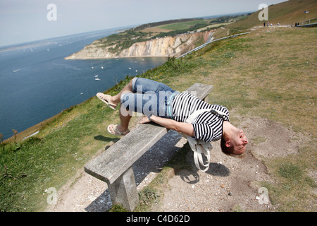 Mann mit gestreiften t-Shirt im Urlaub lehnt sich zurück auf eine Klippe Top Bank Spaß und stretching - Modell veröffentlicht Stockfoto